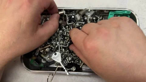 Hands sorting through metal screws, bolts and small hardware fasteners  Vidéo 344782658