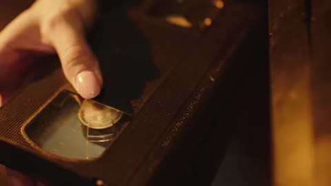 Hands sorting through old video cassettes in the evening lighting 스톡 동영상 241784961
