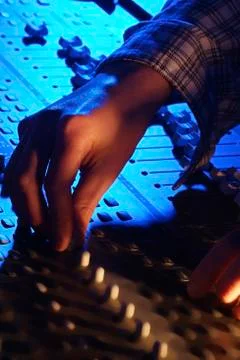 Hands of a sound engineer adjusting the regulators of a professional mixer un Stock Photos