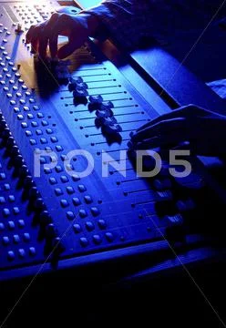 Hands of a sound engineer adjusting the regulators of a professional mixer un Stock Photos