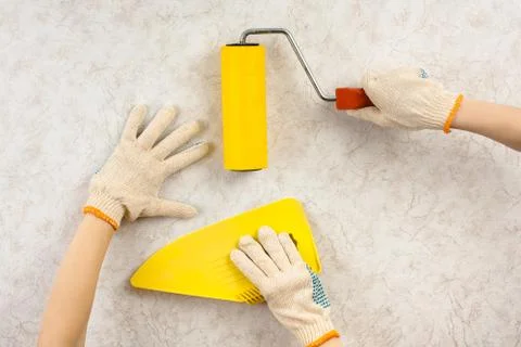 Hands with spatula and roller smoothing wallpaper Stock Photos
