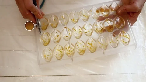 Hands spraying the color to the candy forms slow motion Stock Footage 74476282