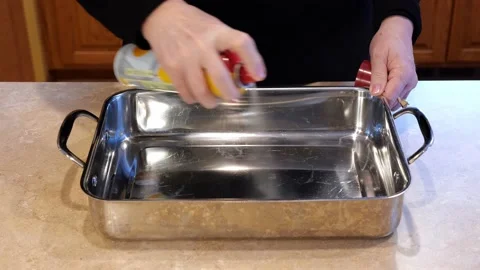 Hands spraying non stick spray in to a baking pan. Stock Footage 153435559