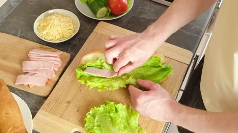 Hands spread ham on a sandwich bun Stock Footage 152093784