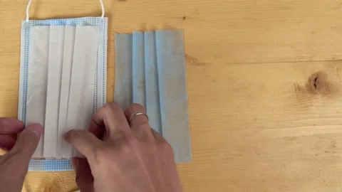 Hands spread out show layers cut clean medical mask to demonstrate its structure Stock Footage 159582456