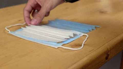 Hands spread out show layers cut clean medical mask to demonstrate its structure Stock Footage 159582499