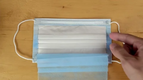 Hands spread out show layers cut clean medical mask to demonstrate its structure Stock Footage 162544202