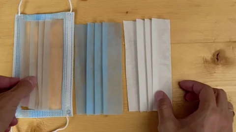 Hands spread out show layers cut clean medical mask to demonstrate its structure Stock Footage 162544297