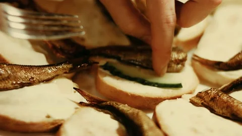 Hands spread tomatoes and cucumbers on bread butter. We take the sprats wit Stock Footage 233454770