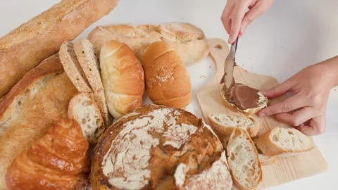 Hands Spreading Chocolate Hazelnut Cream on Fresh Bread Slice Stock Footage 337519461