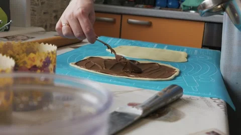 Hands Spreading Chocolate Paste on Rolled Dough for Baking Muffins at Home Video stock 334119758