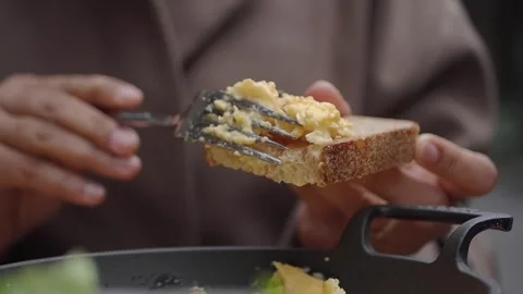Hands Spreading Scrambled Eggs onto a Piece of Toast Stock Footage 335065559