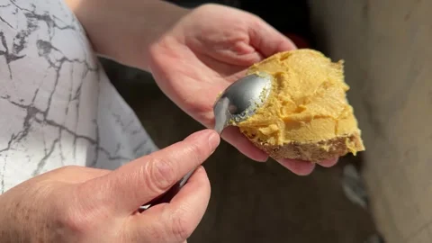 Hands spreading yellow peanut butter or cheese spread on bread  Stock Footage 345327588
