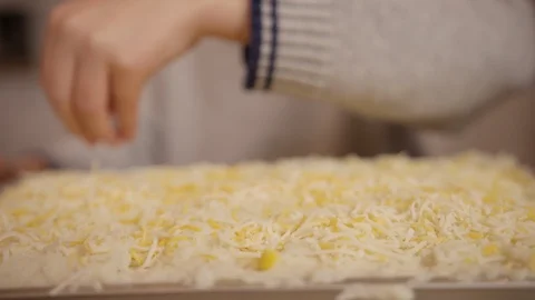 Hands sprinkle cheese on top of casserole or pizza before going into oven Stock Footage 123738513