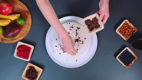 Hands Sprinkling Chocolate and Nuts on Dessert in Kitchen Vidéo 342848352