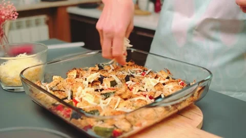 Hands sprinkling grated cheese on roasted vegetables in kitchen Stock Footage 342888626