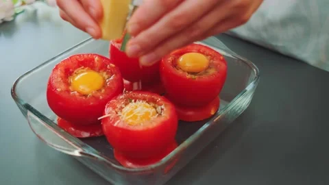 Hands sprinkling grated cheese on stuffed tomatoes in kitchen 库存影片 342878247