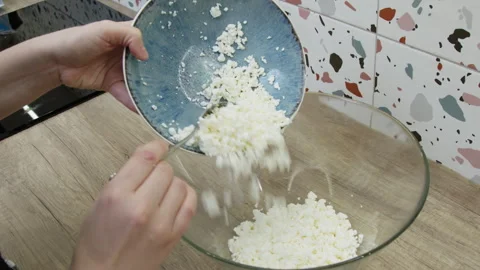 Hands sprinkling pot cheese from a plate into a bowl. Stock Footage 266423913