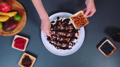 Hands Sprinkling Sliced Almonds on Chocolate Dessert Indoors 库存影片 342850460