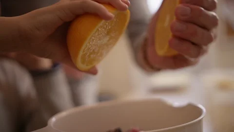 Hands squeeze bright orange slices for juice into bowl Stock Footage 123738153