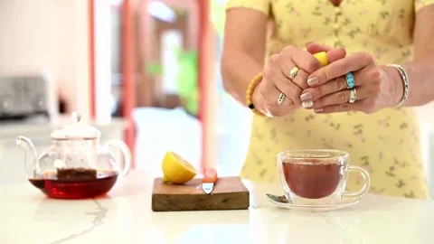 Hands squeeze out lemon juice from a slice into a glass with lemon water. Stock-Footage 336588747