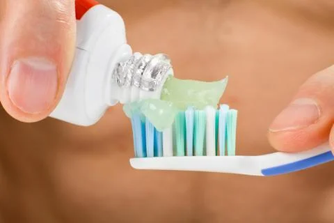 Hands squeeze toothpaste onto a toothbrush Stock Photos