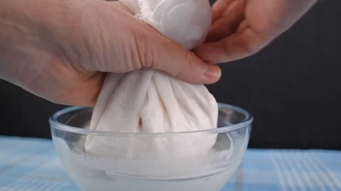 Hands of squeezing the almond milk bag or cheese cloth. Rotation. 库存影片 124898409