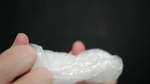 Hands squeezing bubble wrap polyethylene packaging characteristic pop sounds Stock Footage 320896153