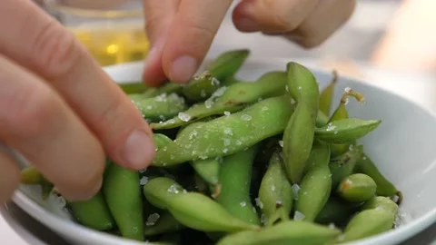 Hands squeezing edamame beans out of pods. Trendy vegan Japanese street food Видео 138152051