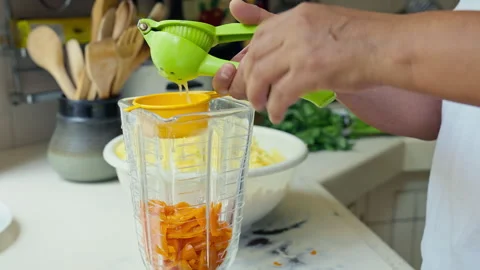 Hands squeezing fresh lime juice using a green manual press into a blender Stock Footage 339078991