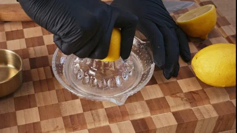 Hands squeezing fresh yellow lemon on manual glass citrus juicer. Stock Footage 344886177