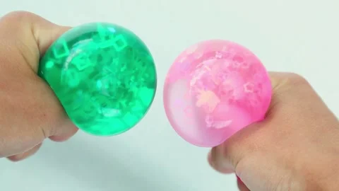 Hands squeezing green and pink water balls on white background Stock Footage 319405992