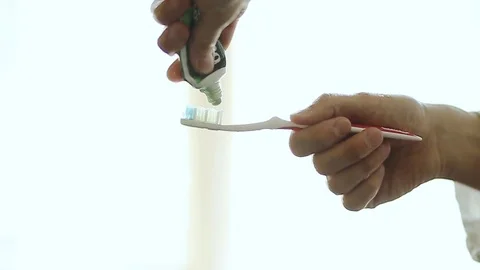 Hands squeezing green toothpaste on a toothbrush in slow motion Stock Footage 76379804