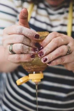 Hands squeezing honey from a plastic bottle Stock Photos