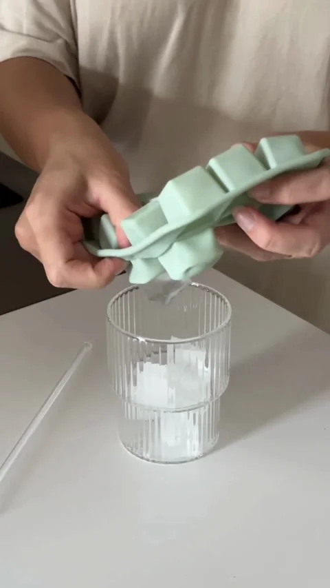 Hands squeezing ice cubes from tray into a glass Video stock 331770356