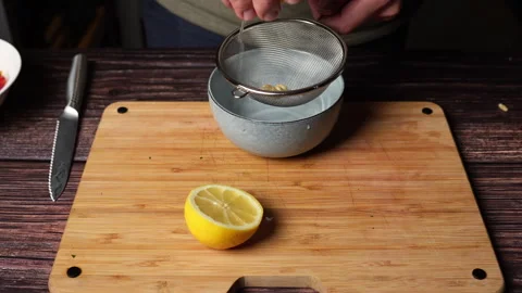 Hands squeezing lemon over sieve with cut lemon below Stock Footage 301446341