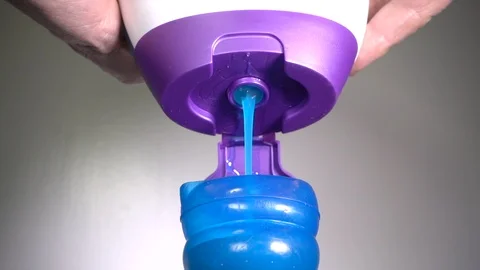 Hands squeezing liquid gel laundry detergent into a small container. Video stock 98744476