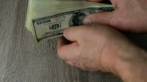 Hands stack many dollars in stack on a wooden table. Aligns stack of bills and Stock Footage 153626321