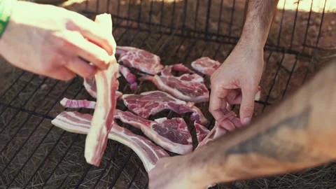 Hands stacking raw meat in grill rack for summer barbecue Stock Footage 181878919
