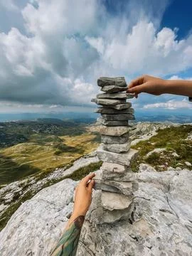 Hands Stacking Stones for Cairn Tower in Mountains Stock Photos