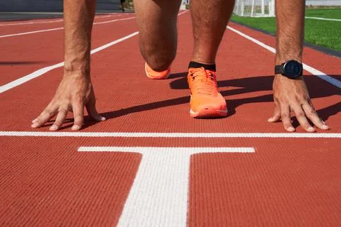 Hands on the starting line, the sprinter is preparing to start at the stadium. Stock Photos