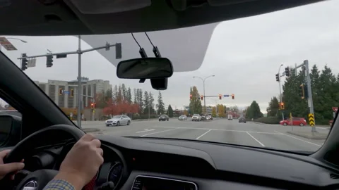 Hands on the steering wheel of a car driving through the city Stock Footage 137931173