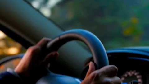 Hands on steering wheel driving car at golden sunset Video stock 332275158