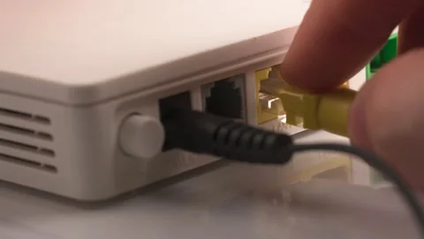 Hands stick out yellow patch cord LAN cable in router Stock Footage 237824245