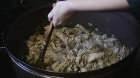Hands stirring meat inside big pot in slow motion Stock Footage 44324897
