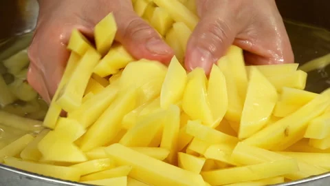 Hands Stirring Raw Potato Strips in Water Bowl Stock Footage 343971572