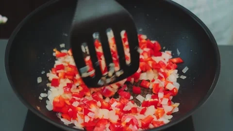 Hands Stirring Sautéed Bell Peppers and Onions in Kitchen Frying Pan Vidéo 342881142