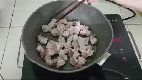 Hands Stirring Sizzling Pork in Pan on Electric Stove in Vietnam Kitchen Vídeos de archivo 336007550