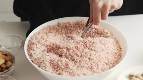 Hands stirring uncooked rice tinted with spice mixture in a shallow bowl, s.. Stock Footage 332159831