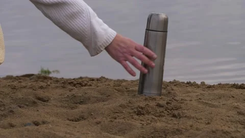 Hands with straw hat and thermos flask on beach 스톡 동영상 153512971